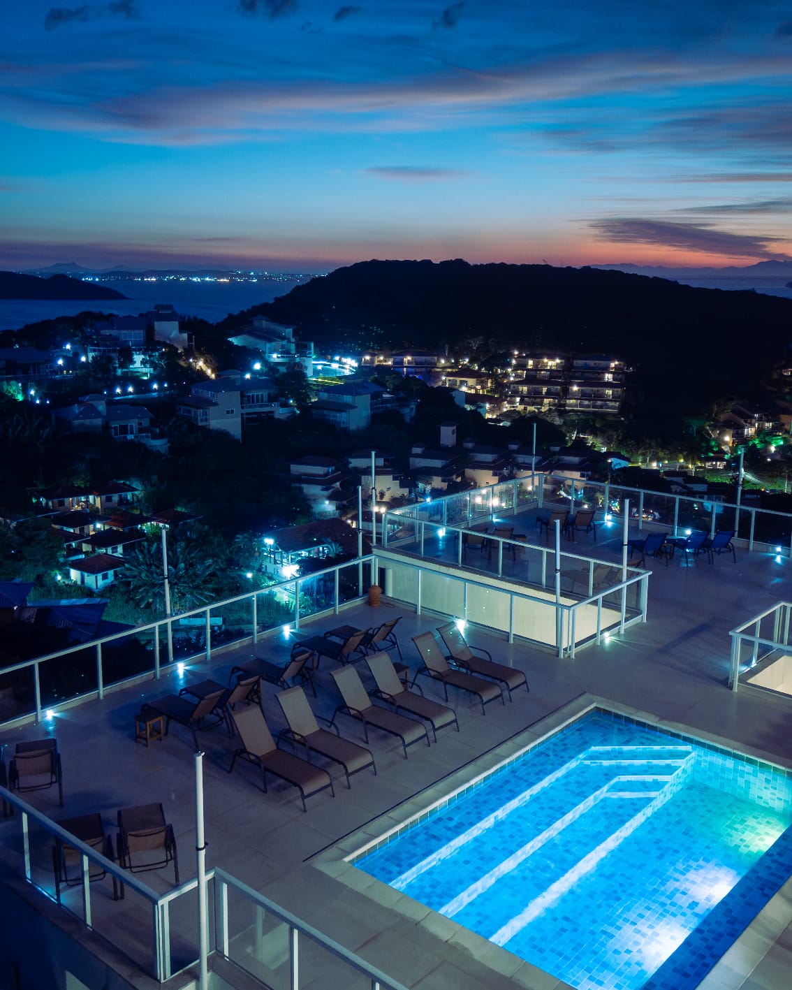 Guarda-corpo de vidro da Pousada Santorini em Búzios/RJ iluminado à noite junto à piscina