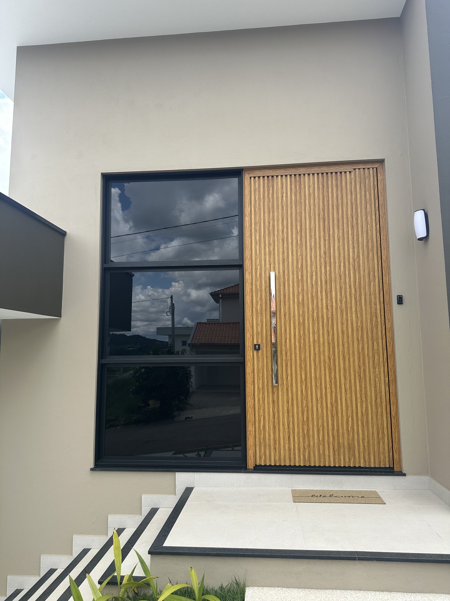 Porta principal pivotante em lambril ripado amadeirado instalada pela Perffec em Bragança Paulista